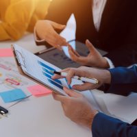 Meeting of business executives discussing analysis of the company's financial situation and business planning with partner collaboration and consultation of strategy.